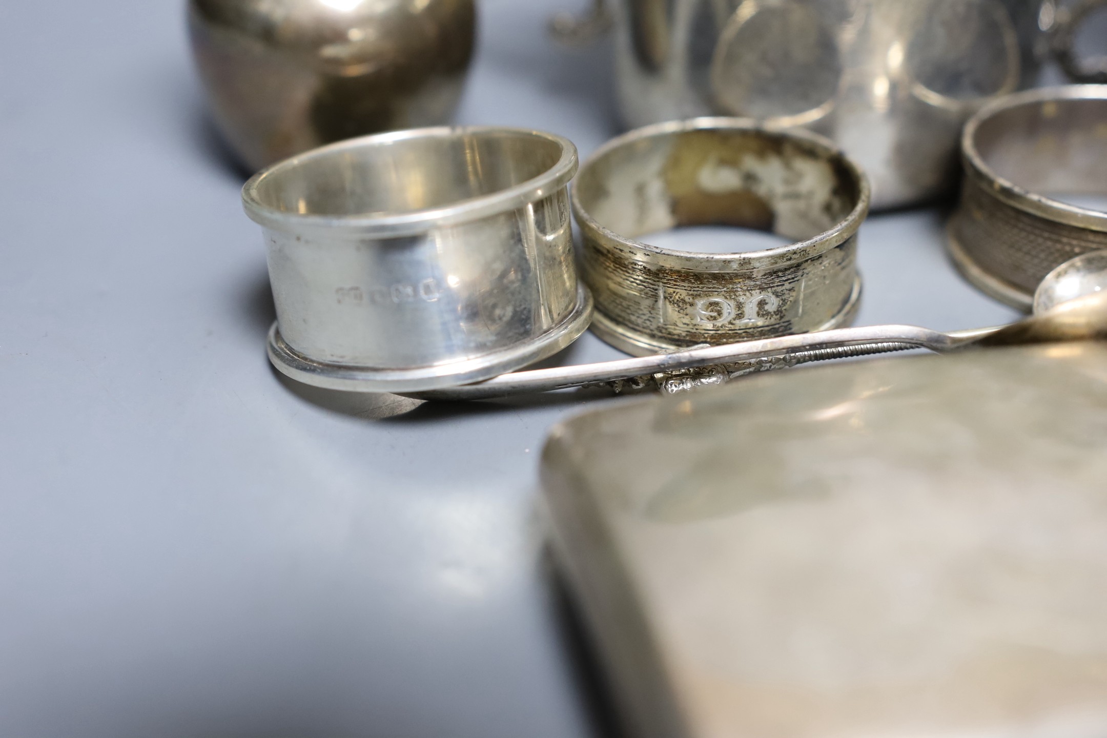Assorted silver including a pair of posy vases, a small porringer, a pierced shallow bowl, a cigarette case, four napkin rings, a bonbon dish and six silver spoons, together with a French white metal cream jug and three